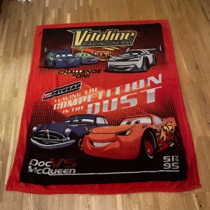 Stor filt (Blixten McQueen) - Bilden visar en filt med motiv från filmen Bilar (Cars) med karaktärerna Lightning McQueen och Doc Hudson. 