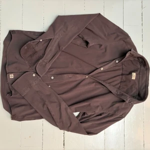 Sonrisa skjorta - Säljer en stilren brun skjorta från Sonrisa. Skjortan är tillverkad i mjuk bomull. Nypris 3000kr.