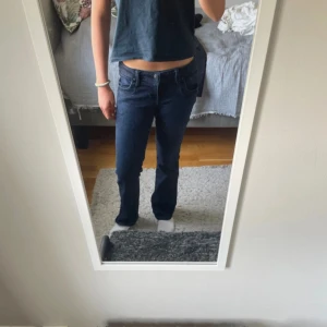 Mörkblå/svarta  bootcut jeans LTB - Säljer ett par mörkblå jeans från LTB i bootcut-modell. Jeansen har klassisk femficksdesign, låg midja och är tillverkade i stretchigt denim för en bekväm passform. Perfekta om du gillar en tidlös look med lite utsvängda ben. Jeansen är insydda och passar mer som 26 eller 25 (man ser inte att de är insydda) 