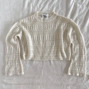 Vit stickad tröja från Paper Heart - Säljer en vit stickad tröja från Paper Heart i storlek L. Tröjan har ett genombrutet, mönstrat stickat material och långa ärmar. Den är croppad och har ribbade muddar vid hals, ärmslut och nederkant. Perfekt för lager-på-lager och en chill look.