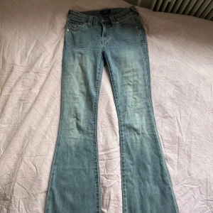 True Religion bootcut jeans ljusblå - Säljer ett par ljusblå bootcut jeans från True Religion, modell Becca Mid Rise. Jeansen har snygga fickdetaljer med knappar bak och klassisk logga på bakfickan. Jeansen är i storlek 24 och passar mig i längden som 172! Jeansen är endast använda fåtal gånger pga felköp, och har inga slitningar!💕(nypris 1 299kr)
