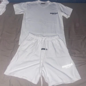   Essentials Fear of God shorts och t shirt - Snyggat set från Essentials med elastisk midja och långa snören framtill. Klassisk loose fit och logga tryckt på benet. Perfekta för chill dagar eller streetwear-stil. Mjukt material som känns skönt mot huden.