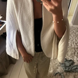 Vit poncho med dragkedja - Stilren vit poncho med grov textur och markerade sömmar. Från Zara 