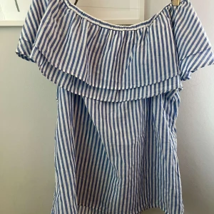 Randig offshoulder topp - Superfin blåvit randig kortklänning från Gina Tricot med offshoulder och volang upptill. Perfekt för sommardagar, luftig och lätt i bomull. Säljer då den var lite stor för mig💕Pris kan diskuteras💕