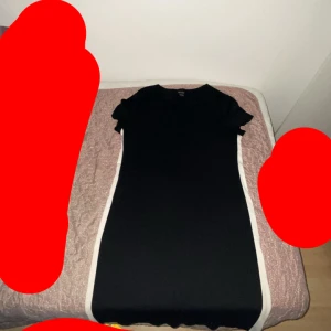 Svart kortklänning med vita sidor - En svart kortklänning med vita paneler längs sidorna. Klänningen har rund halsringning och korta ärmar med lätt volang. Enkel och stilren design som ger en sportig och fräsch look. Och den är storleken S