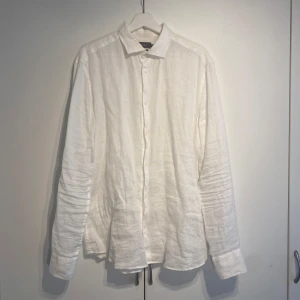 Vit linneskjorta från Riley - Klassisk vit linneskjorta från Riley i 100% linne. Skjortan har lång ärm, knappar framtill och en avslappnad passform. Perfekt för en clean och fräsch look, särskilt under varmare dagar. Enkel och stilren design som funkar till många outfits. Storlek Large och True To Size. Nypris 900kr. Fint skick, sparsamt använd. Hör av dig för fler bilder! 