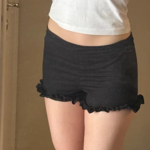 Svarta volangshorts med stretch - Supersöta svarta shorts med volangkant nertill och stretchigt tyg. Aldrig använda 