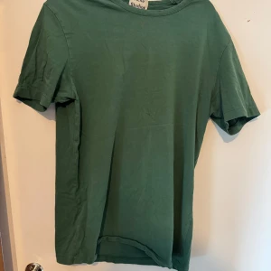 Grön t-shirt från Acne Studios - Enkel och stilren grön t-shirt från Acne Studios i 100% bomull. Klassisk passform med rund halsringning och korta ärmar. Perfekt för dig som gillar minimalistisk och clean stil.
