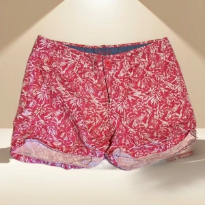 Rosa blommiga shorts med vit mönster - Snygga rosa shorts med vitt blommigt mönster och klassisk knappstängning fram. De har en avslappnad passform och är perfekta för varma dagar. Shortsen har fickor och är tillverkade i ett lätt material som känns skönt mot huden.
