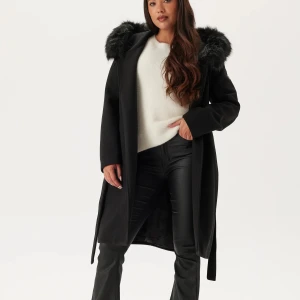 Svart kappa med fuskpäls och huva från Hollies  - Super snygg lång kappa med päls huva. Använd endast 2 h på en begravning. Köpt för 1699kr. Säljer för 1200, kan gå ner i pris vid snabb affär.  Storlek 32