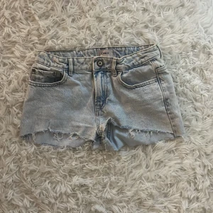 Ljusblå jeansshorts från ONLY - Snygga ljusblå jeansshorts från ONLY med råa, fransiga kanter och klassisk femficksdesign. Shortsen har justerbar midja på insidan och en avslappnad passform. Perfekta för sommardagar och ger en cool, avslappnad vibe. storlek 158 men skulle säga att de är som XS 
