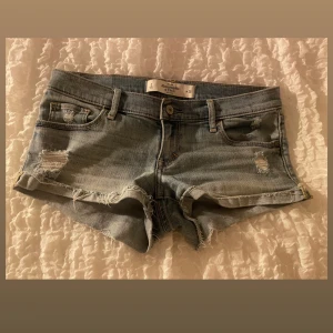 Lågmidjade jeansshorts Abercrombie - Bildena va felvända därför blev dom konstiga. Snygga ljusblå jeansshorts från Abercrombie & Fitch med låg midja och råa, fransiga kanter. Shortsen har slitna detaljer och klassiska fickor både fram och bak. Perfekta för varma sommardagar och en avslappnad look.