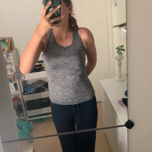 Grå tränings topp 💍 - Säljer ett gråmelerat träningslinne. Toppen är ärmlös med sportig racerback och har en slim passform som sitter snyggt mot kroppen. Perfekt för träning eller chill dagar. Materialet är mjukt och stretchigt syntet för maximal komfort.💓