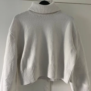 Vit polotröja från H&M, stickad XS - Supermysig vit polotröja från H&M i stickat material. Tröjan har en hög, ribbad polokrage och breda ribbade muddar vid ärmslut och nederkant. Perfekt för lager-på-lager och chill höst- eller vinterstil.