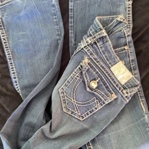 Blå jeans från LA Idol USA med slitningar - Säljer ett par blå jeans från LA Idol USA med markerade kontrastsömmar dock slitningar vid bensluten. Jeansen har fickor med stenar och söm design  . Pris kan diskuteras . Säljer då dem är förstora för mig 