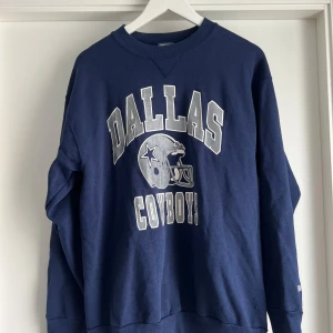 Dallas Cowboys sweatshirt i marinblå XL - Snygg marinblå vintage Dallas Cowboys sweatshirt från Bike i storlek XL. Tröjan har tryck med lagets logga och text i vitt och grått framtill. Tillverkad i en mjuk mix av bomull och polyester, perfekt för dig som gillar sportig och avslappnad stil.