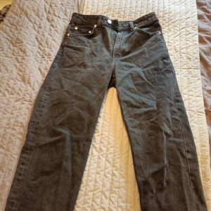 Svarta Weekday Lash mom jeans 27/28 - Säljer ett par svarta Lash Extra High Mom Jeans från Weekday i storlek 27/28. Jeansen har hög midja, raka ben och klassisk femficksdesign. Tillverkade i bomull med dragkedja och knapp framtill. Perfekta för en chill och stilren look.