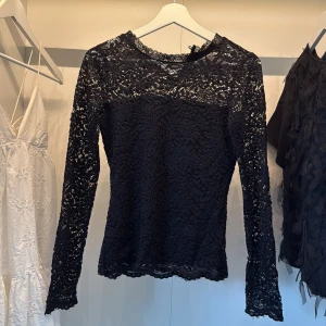Svart spetsblus med lång ärm - Supersnygg svart blus i spets med långärmad passform och rund hals. 