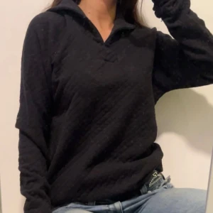 Svart quiltad långärmad tröja - Svart långärmad tröja med quiltad struktur och krage. Storlek M 