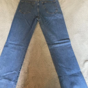 Blå raka jeans i klassisk modell - Säljer ett par blå jeans med rak passform. Jeansen har normal midja och är tillverkade i tåligt denimtyg. Perfekta för dig som gillar en tidlös och avslappnad stil.