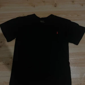 Svart Ralph lauren T-shirt  - Säljer denna svarta Ralph lauren T-shirt i mycket god skick. Helt perfekt och stilig T-shirt för den som vill skina på sommarn 