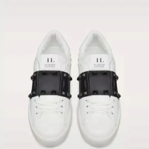 Valentino Garavani Rockstud sneakers - Snygga vita sneakers från Valentino Garavani med svart band och ikoniska pyramidformade nitar över vristen. Skorna är i skinn och har en chunky sula med coola detaljer. Perfekta för dig som vill sticka ut med en edgy och lyxig vibe. Nypris 8500kr men skon har en liten skada därför säljer jag för billigare fråga om mer bilder