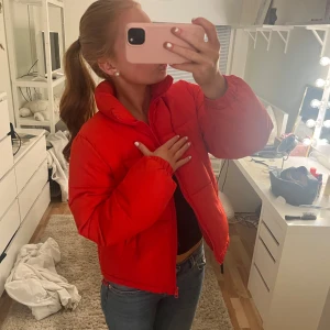 Röd pufferjacka - Säljer en snygg röd pufferjacka med dragkedja. Jackan har en hög krage och långa ärmar, perfekt för kyligare dagar. Den är både stilren och bekväm, ett måste i garderoben! Storlek 158/164 från Gina, passar mig som har storlek XS/S