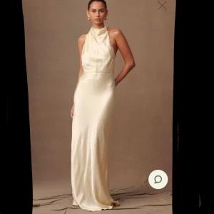 Ljusgul långklänning - Elegant ljusgul maxiklänning i satin med halterneck och öppen rygg. Klänningen har en smickrande passform och knappar längs ryggen för en stilren look. Passar perfekt till både bal och bröllop☀️klänningen är köpt för 1600 kr och säljer den eftersom den inte passade vad jag sökte. Detta är klänning 2/2 (beställde hem samma klänning i 2 storlekar)