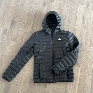 Svart dunjacka från Adidas - Säljer nu denna svarta dunjacka från Adidas | Skick 10/10 | Den har används fåtal gånger och har inga defekter | Storlek XS | Vid frågor är det bara att höra av sig!