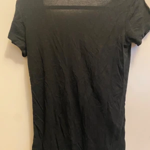 Svart t-shirt med v-ringning - Säljer en stilren svart t-shirt med djup v-ringning. Perfekt för en avslappnad look. Kortärmad och i ett mjukt material som känns skönt mot huden.  Den är öppen i ryggen jätte fin från lager 157