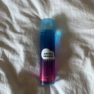 Ariana Grande Cloud Body Mist - Säljer en Ariana Grande Cloud body mist i en stilren flaska med blå och rosa gradient. Flaskan rymmer 236 ml och har en praktisk sprayfunktion. Perfekt för att fräscha upp din doft under dagen.