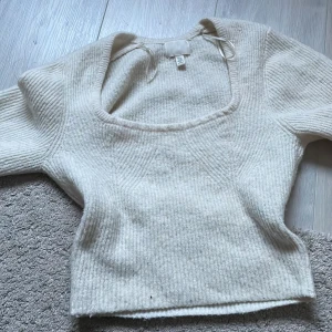 Vit stickad tröja från H&M - Säljer en mysig vit stickad tröja från H&M. Tröjan har en fyrkantig halsringning och långa ärmar, perfekt för kyliga dagar. Den är både stilren och bekväm, ett måste i garderoben! 🧶
