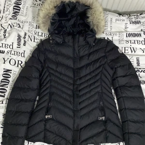 Svart dunjacka från Moncler - Snygg svart dunjacka från Moncler med pälskantad huva. Jackan har en quiltad design och dragkedjor på fickorna. Perfekt för kyliga dagar med stil.helt ny har använt den 2 gånger sen ja köpte den.