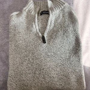 Grå stickad tröja från Chaps - Säljer en stilren grå stickad tröja från Chaps med dragkedja vid halsen. Perfekt för kyliga dagar med sin mjuka och bekväma passform. Tröjan har långa ärmar och en klassisk design som passar till det mesta. Hör av dig vid intresse!