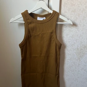 Brun ribbad linnetopp från Vila  - Säljer en snygg brun ribbad linnetopp från Zara. Toppen är ärmlös och har en tight passform, perfekt för varma dagar. Den har en enkel och stilren design som passar till det mesta.