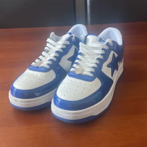 Dark Blue Bapestas Skor - Snygga BAPE STA sneakers i blått och vitt. Skorna har en glansig finish med den ikoniska stjärndetaljen på sidan. De är utrustade med vita snören och har en bekväm passform.                                                                                 Är villig på att diskutera om priset.