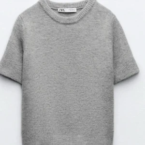 Grå stickad tröja från Zara - Säljer en stilren grå stickad tröja från Zara. Tröjan har korta ärmar och en rund halsringning, perfekt för lager-på-lager eller som den är. Den mjuka stickningen ger en bekväm känsla. Passar till både jeans och kjol!