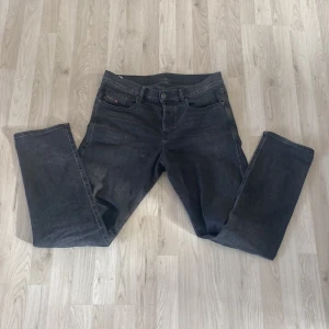 Grå jeans från Diesel - Snygga grå jeans från Diesel med en klassisk femficksdesign. De har en knappgylf och är tillverkade i ett slitstarkt denimtyg. Perfekta för en stilren look.