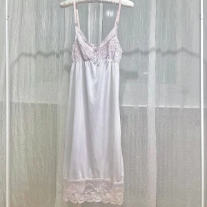 Vit nattklänning med spetsdetaljer - Elegant vit klänning med vackra spetsdetaljer vid byst och fåll. Justerbara axelband för perfekt passform. Passar storlek 32-36.