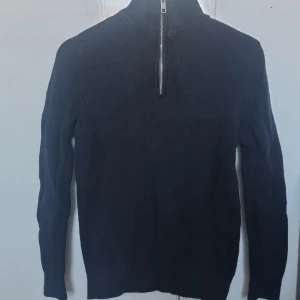 Svart half zip i storlek S - Säljer en svart ribbad tröja från H&M i slim fit med dragkedja framtill. Perfekt för en stilren look. Tröjan har långa ärmar och en hög krage. Skick på 8/10 utan några defekter. Dens material är i bomull. 
