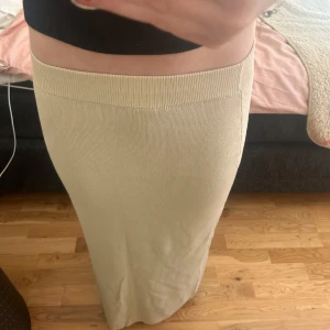 Beige stickad långkjol - Säljer en stilren beige stickad långkjol. Kjolen har en ribbad midja och är perfekt för en elegant look. Passar bra till både vardag och speciella tillfällen.
