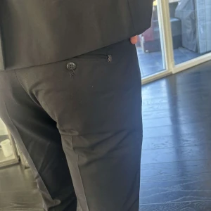 Svarta kostymbyxor - Snygga svarta kostymbyxor med klass. Perfekt för formella tillfällen. Kavajen har en klassisk passform och byxorna är stilrena med en smal siluett. Passar utmärkt till studenten. 