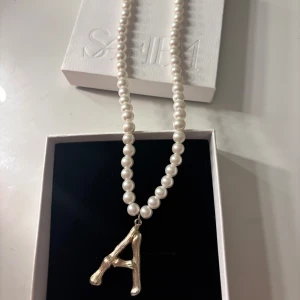 Pärlhalsband med bokstav - Ett superfint halsband med pärlor och en A-bokstav i guldfärg🤍