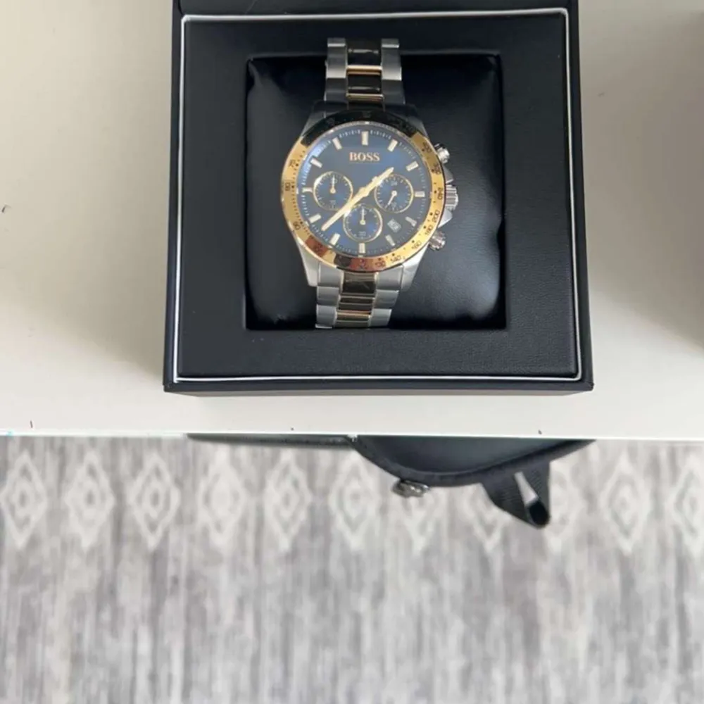Säljer en snygg och stilren Hugo Boss Hero Sport 1513767 klocka i nyskick. Klockan har en elegant kombination av silver och guld, med en blå urtavla och flera sub-dials. Länkarmbandet är i robust metall och ger en exklusiv känsla. ✔️ Märke: Hugo Boss ✔️ Modell: Hero Sport 1513767 ✔️ Färg: Silver/guld med blå urtavla ✔️ Storlek: 45 mm ✔️ Skick: Mycket bra, knappt använd ✔️ Tillbehör: Originalbox, certifikat, extra länkbitar Perfekt för den stilmedvetna som vill ha en klassisk och tidlös klocka! . Asusteet.