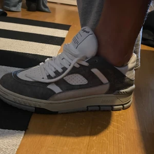 Axel Arigato sneakers i grått och vitt - Snygga sneakers från Axel Arigato i en clean kombo av grå mocka och vitt skinn. Nypris:3500kr kartong ingår. Använt 3-4 gånger bara