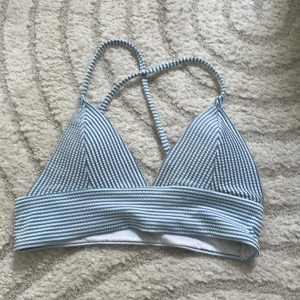 Blåvit randig bikiniöverdel - Supersöt bikiniöverdel med smala blå och vita ränder och smala axelband som korsas i ryggen. Triangelformade kupor och bred resår under bysten ger en sportig och fräsch look. Perfekt för stranden eller poolen i sommar! Pris går att diskutera! 