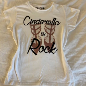 Vit t-shirt Narciso med tryck - Vit t-shirt från Narciso i 100% bomull med coolt tryck framtill: 'Cinderella is Rock' och motiv av klackskor. Klassisk rund halsringning och korta ärmar. Sitter figurnära och är perfekt för dig som gillar statement-plagg.
