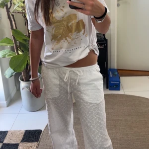 Vita broderade bomullsbyxor H&M XS - Säljer ett par vita byxor från H&M Divided i storlek XS. Byxorna är i 100% bomull med broderade blommor och har snörning i midjan. De är raka i modellen och har en luftig, relaxed fit – perfekta för varma dagar.