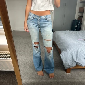 Ljusblå bootcut jeans med slitningar - Selling these low rise ripped 7 for all mankind jeans. The material is very thin and can be easily torn so best for skinny legs. Waist size 26 inches. Shipping from England takes 10 days, shipping included in price. I am 5 feet 6 inches tall for reference and wear size 26/27 waist. 