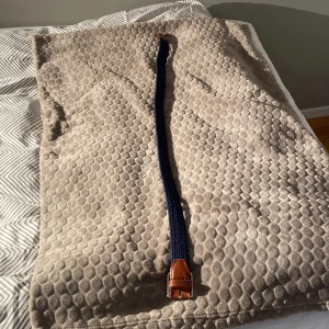Blått flätat bälte från Jack & Jones - Snyggt blått flätat bälte från Jack & Jones med bruna skinn-detaljer och ett silverfärgat spänne. Perfekt för att ge en stilren touch till din outfit. Bältet är både praktiskt och trendigt.